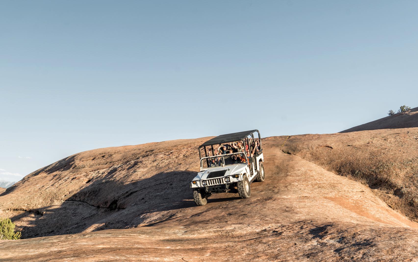 Hummer tour on Hell's Revenge. White hummer descending a sleep section of slickrock on famous Hell's Revenge 4x4 trail in Moab Utah